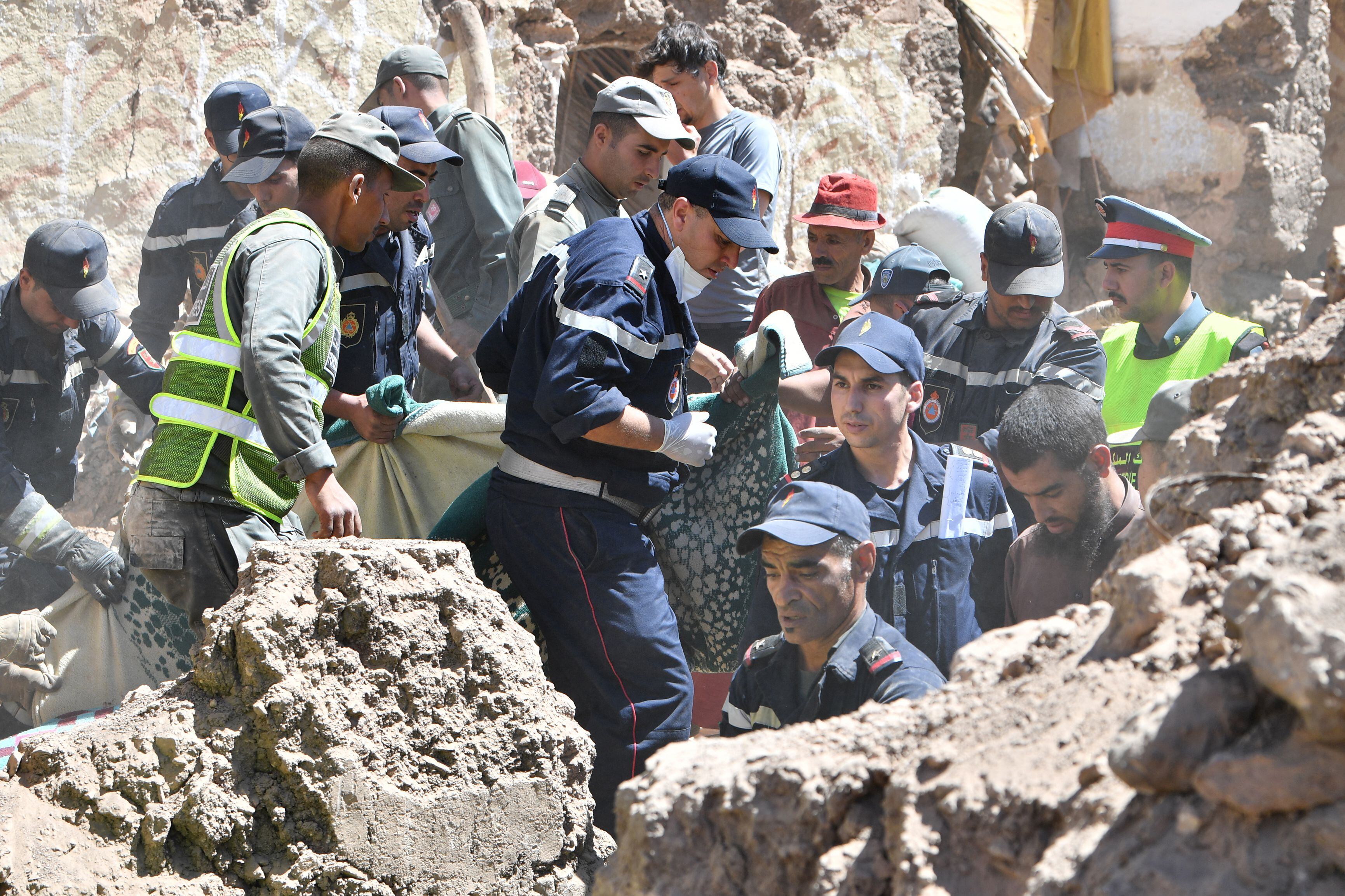 Los socorristas evacuan un cuerpo de debajo de los escombros en la aldea de Tiksit, al sur de Adassil