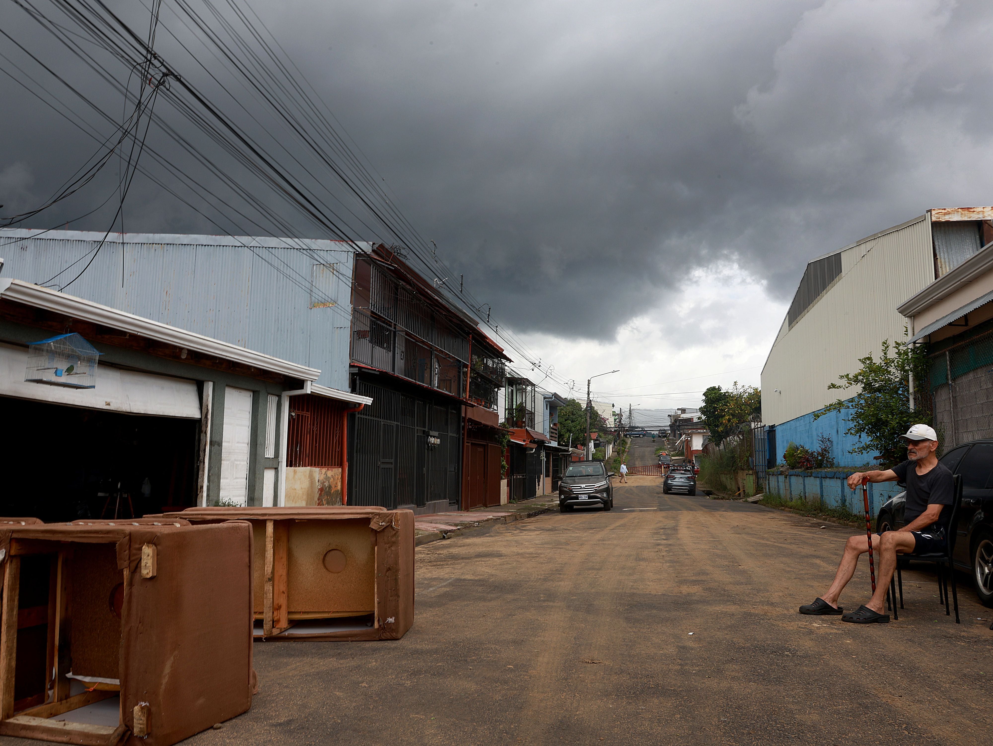 Marco Antonio Guzmán, vecino de Gravilias, sentado en media calle recordó que esa situación la viven año tras año. Al fondo se apreciaba una nube negra que presagiaba más lluvias. Foto: 