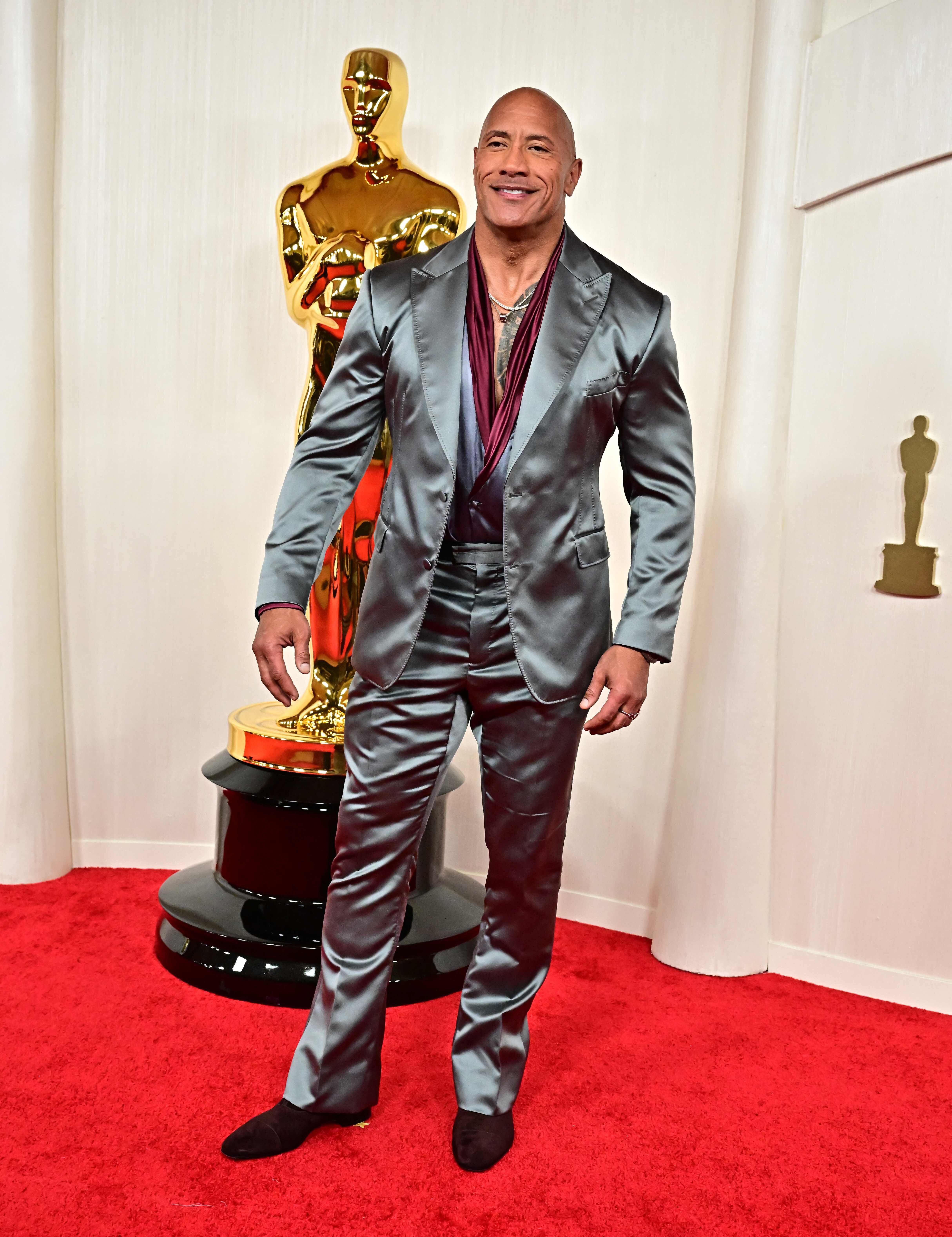 Dwayne Johnson, la Roca, llegó al Dolby Theatre vistiendo un traje plateado metálico con una camisa en color vino. 