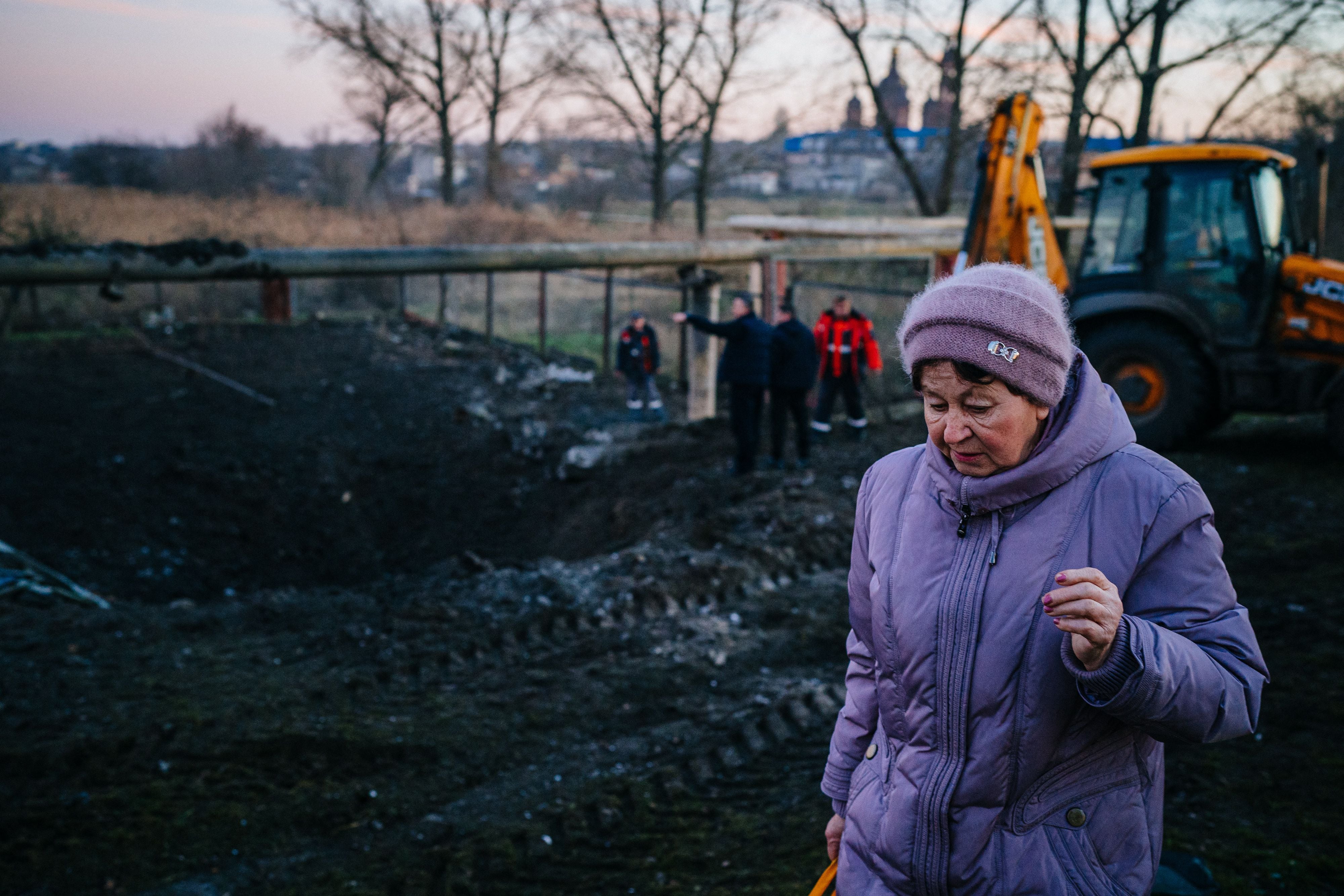 Una mujer pasa junto a un cráter dejado por un ataque con misiles rusos en la ciudad sureña de Mykolayiv, en medio de la invasión rusa de Ucrania