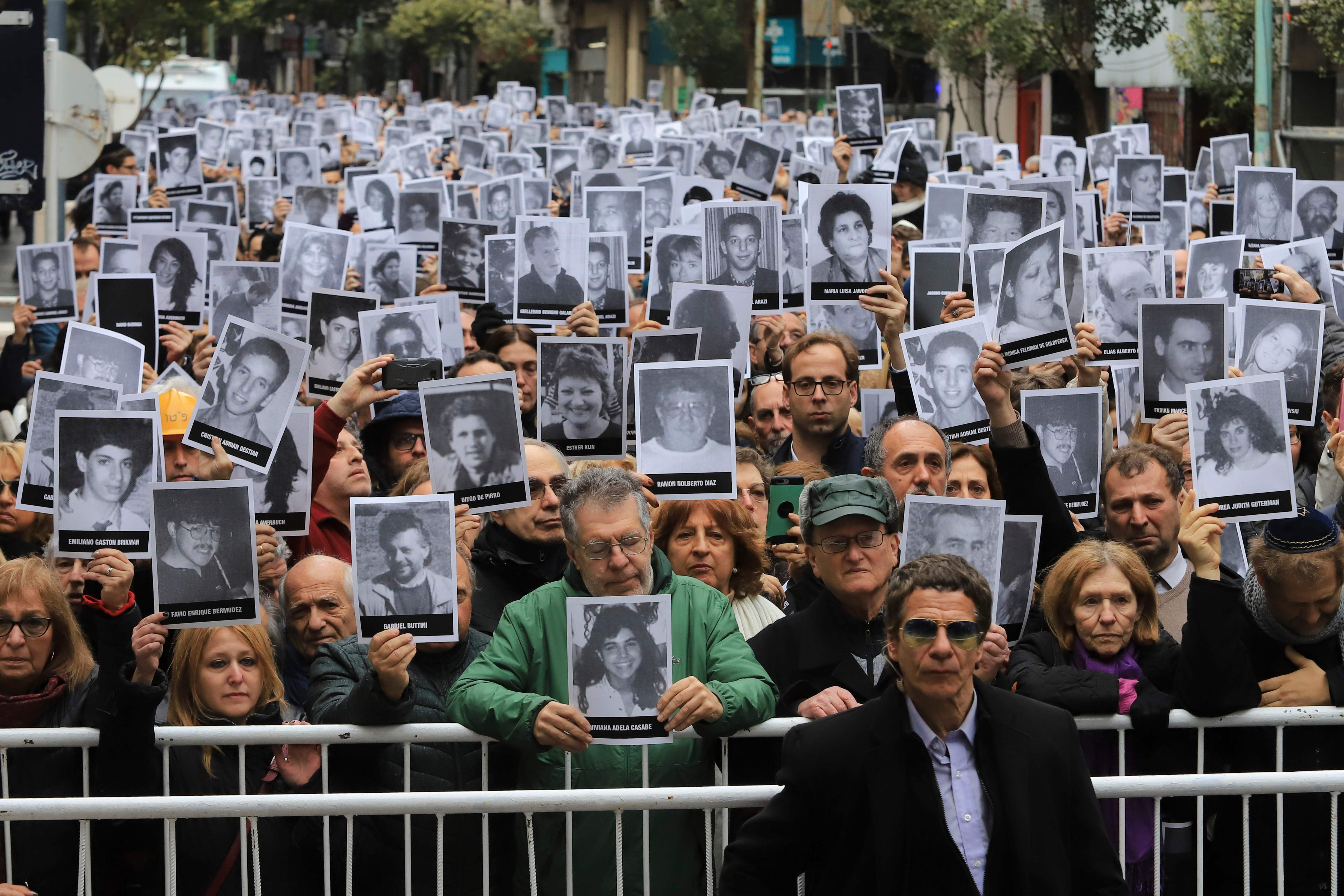 Personas con fotografías de las víctimas del atentado de 1994 contra el centro comunitario judío de la Asociación Mutual Israelita Argentina (AMIA).