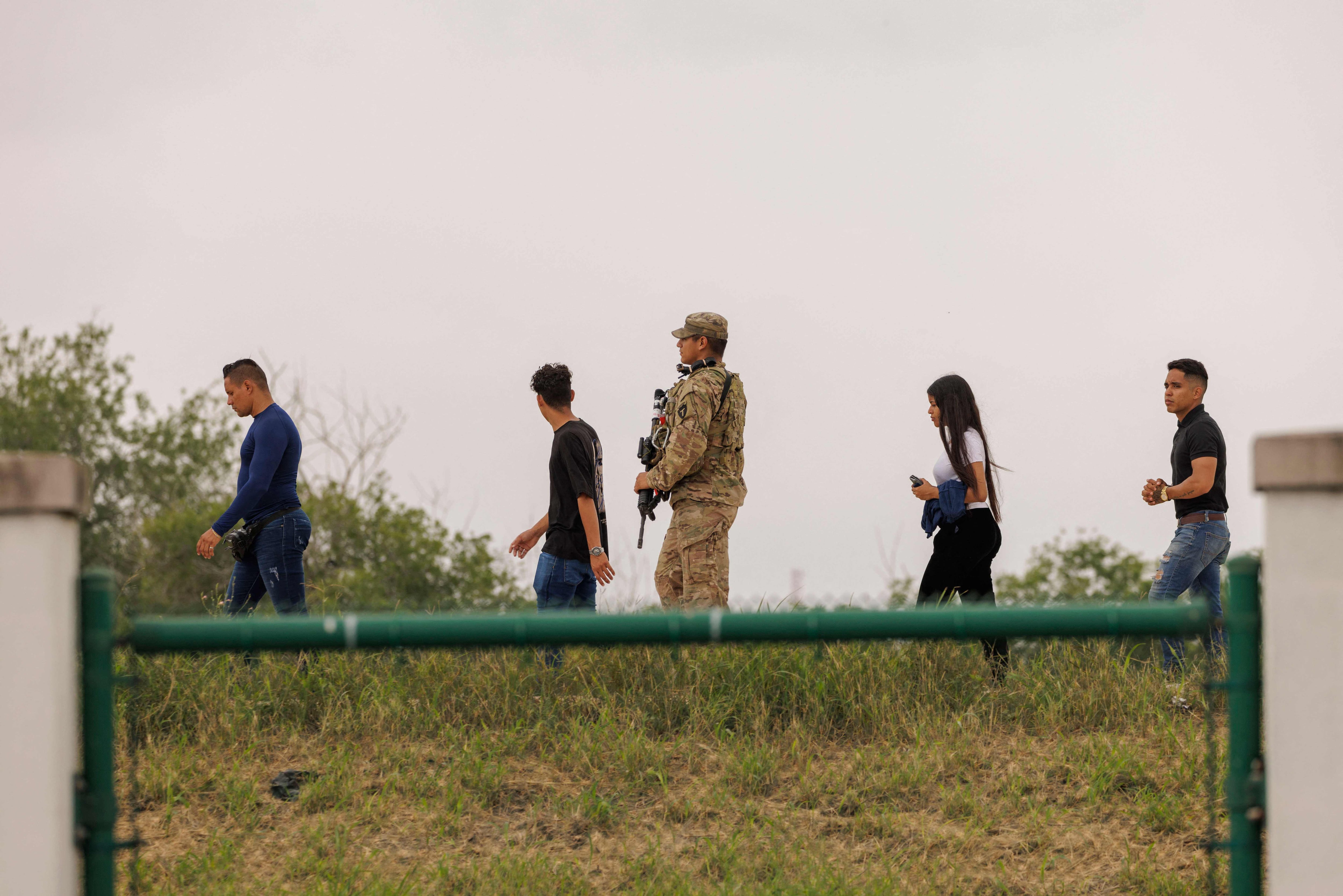 Un miembro de la Guardia Nacional de Texas escolta a los migrantes a los agentes de la Patrulla Fronteriza.