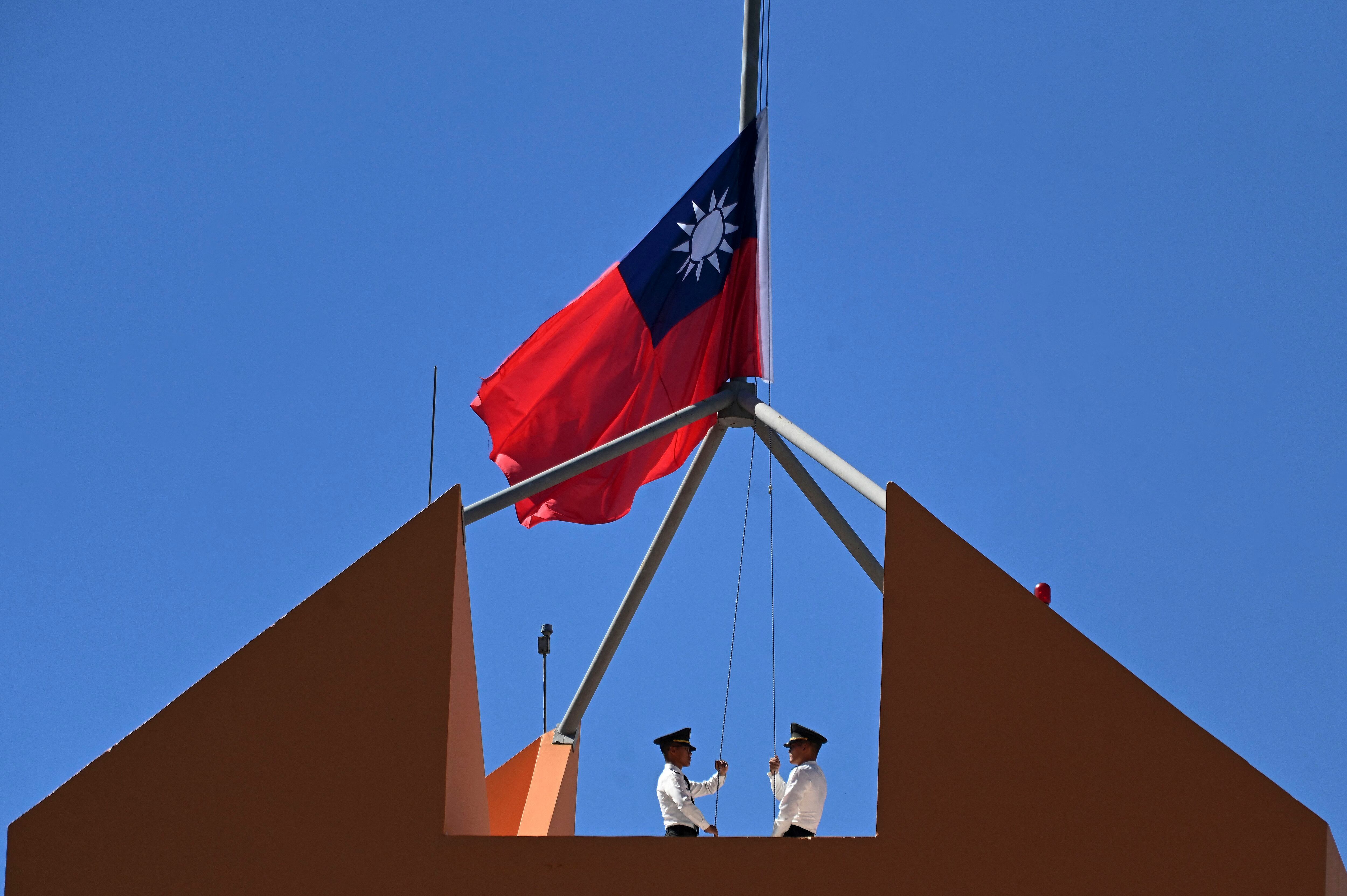 El personal del cuerpo de marines de Taiwán baja la bandera nacional de Taiwán desde el techo de la Embajada de Taiwán en Tegucigalpa. China y Honduras comenzaron relaciones diplomáticas formales el domingo. 