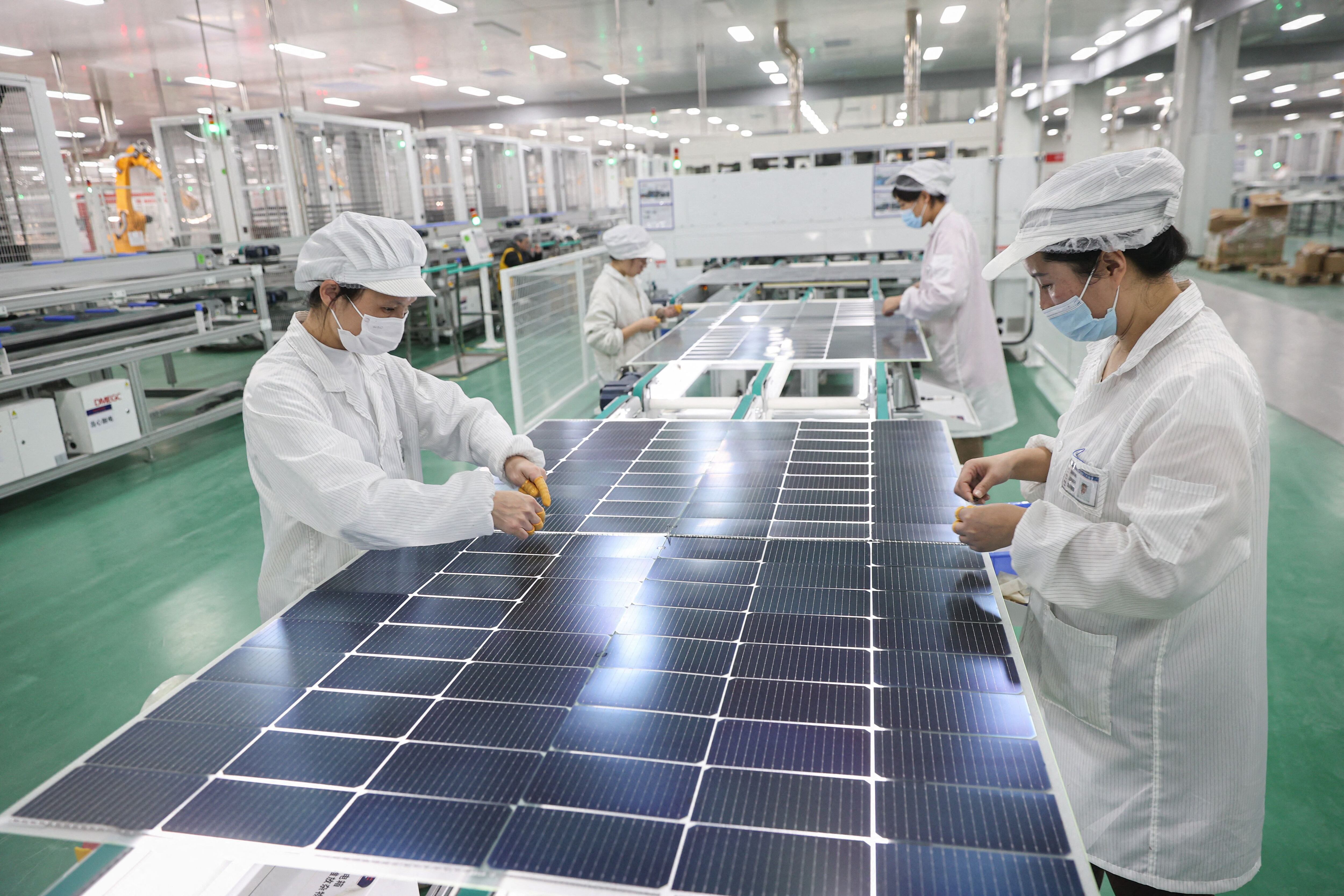 Esta fotografía muestra a los empleados trabajando en módulos solares fotovoltaicos que se exportarán en una fábrica en Lianyungang, en la provincia oriental china de Jiangsu.
