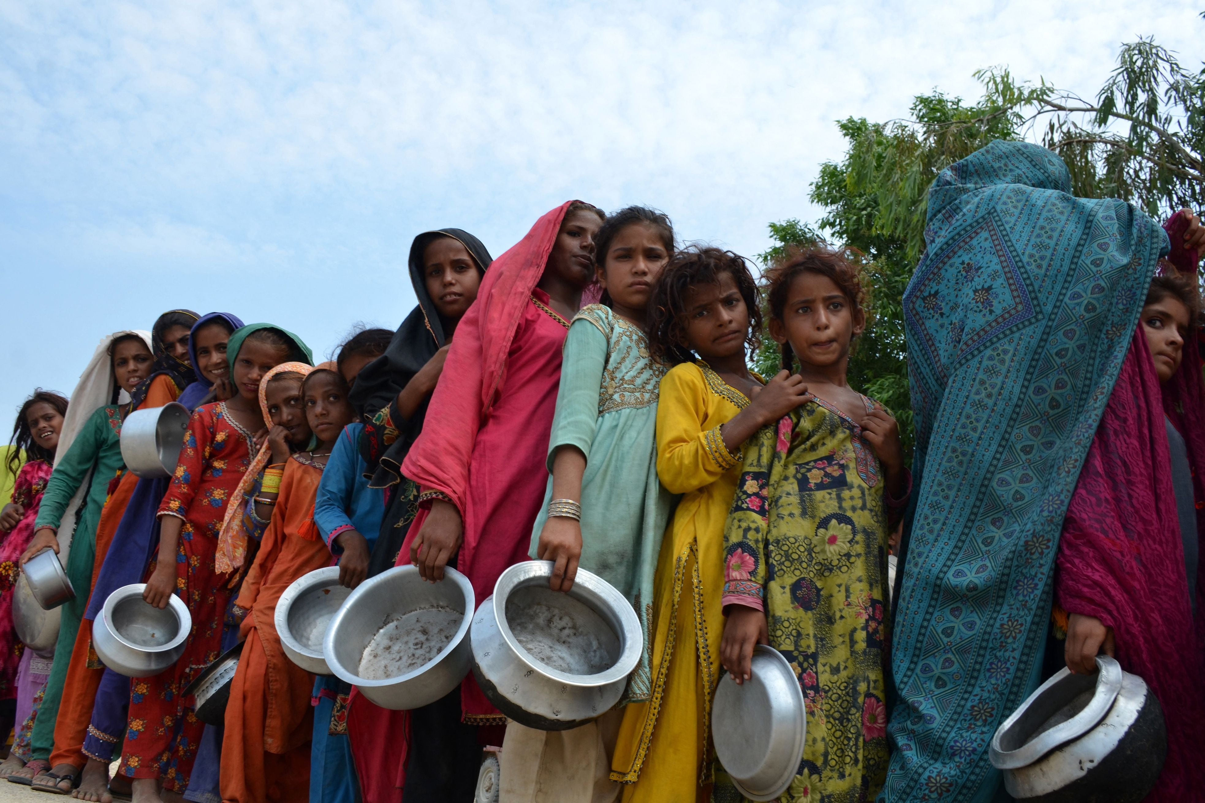 Las personas desplazadas afectadas por las inundaciones hacen cola para recibir los alimentos que distribuye Saylani Welfare Trust en un campamento improvisado en Sehwan, provincia de Sindh, Pakistán, el 13 de septiembre de 2022. (Foto de Husnain ALI / AFP)