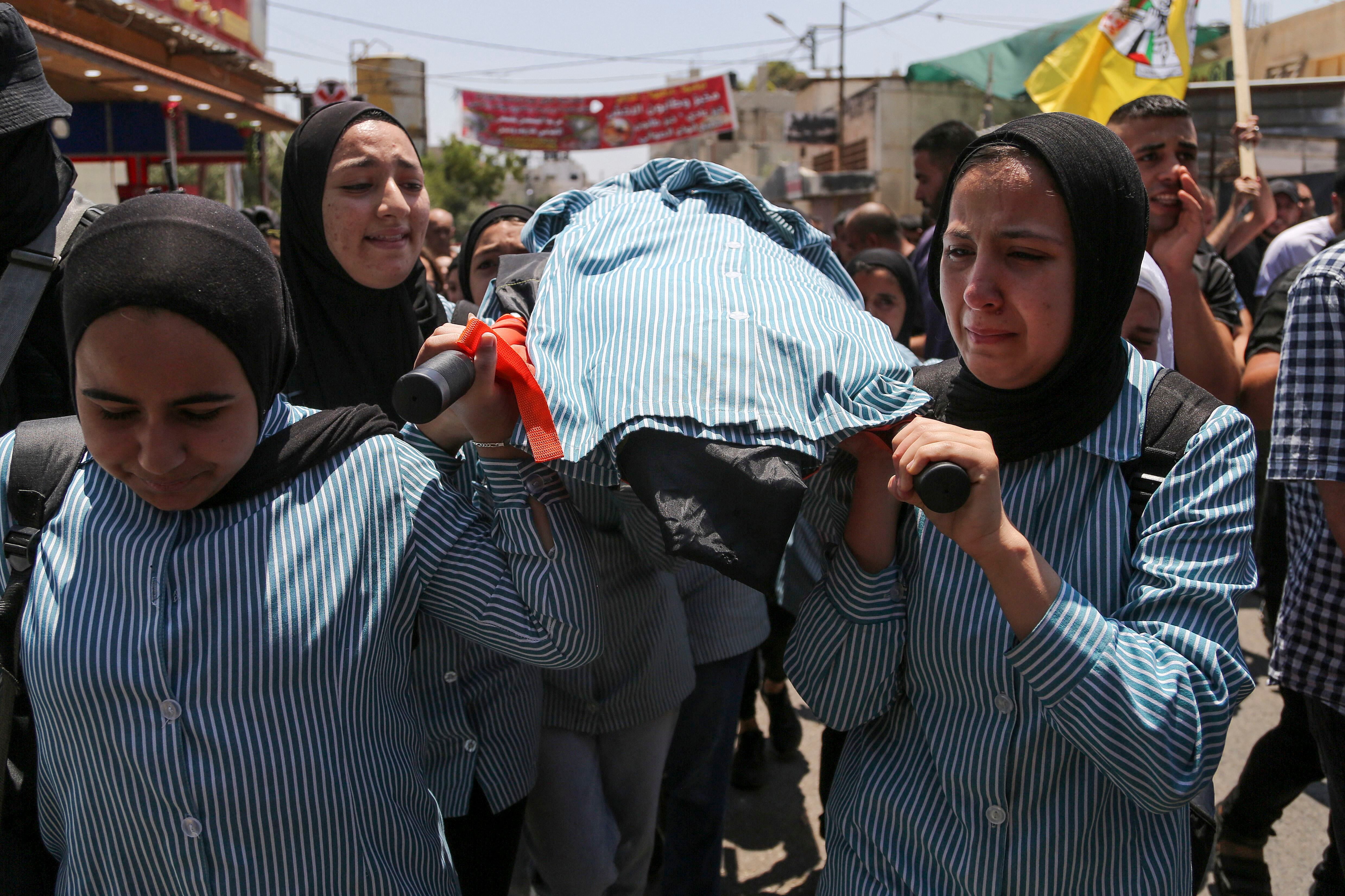 Las niñas de la escuela palestina lloran durante el funeral de su compañero de clase Sadil Naghnaghiya, de 15 años, en Jenin, en la Cisjordania ocupada.