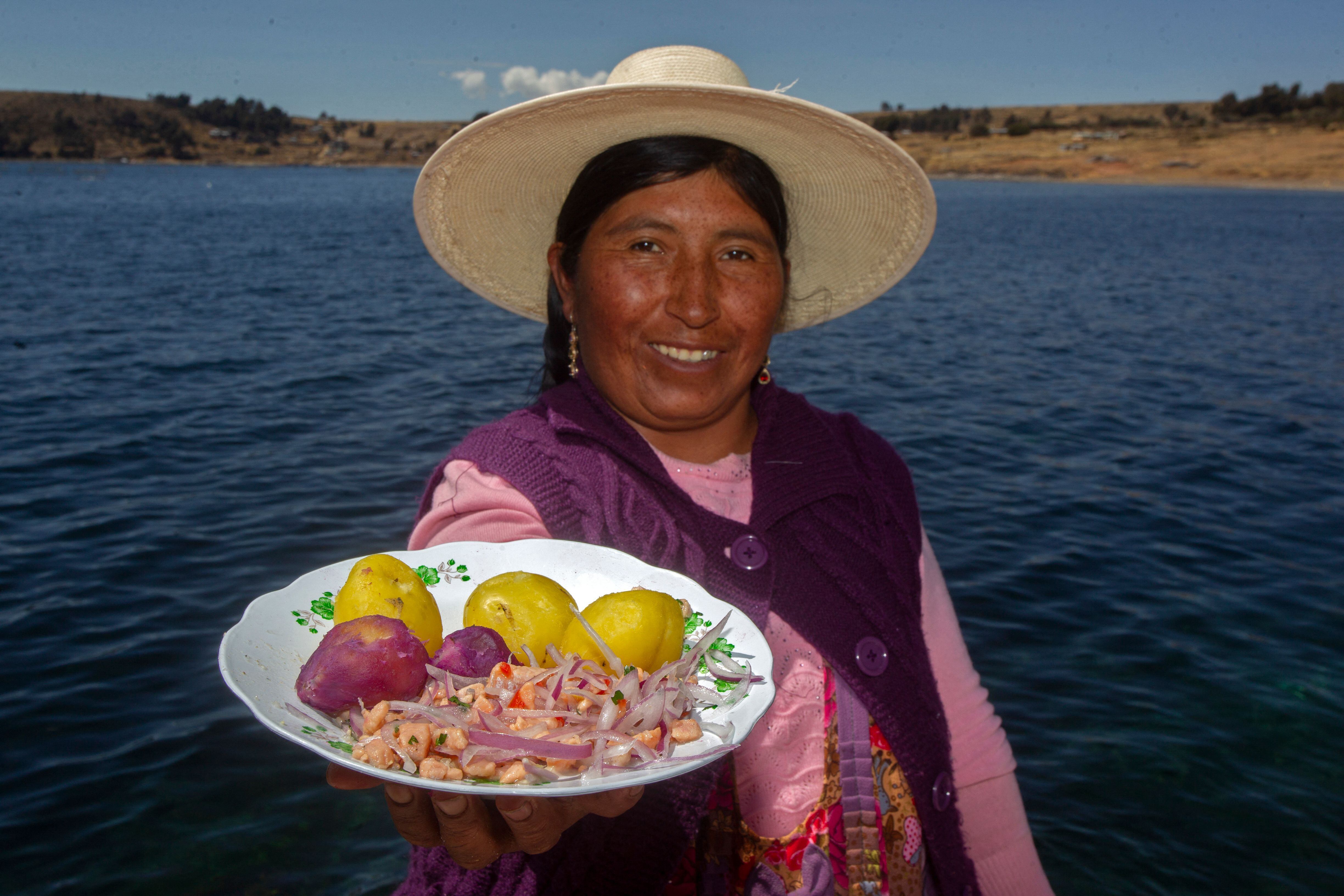 Una mujer muestra un plato con una versión de ceviche, con trucha recién cosechada en una finca en el lago Titicaca, en la comunidad indígena aymara de Chucasuyo, en la sierra andina de Juli, departamento de Puno.