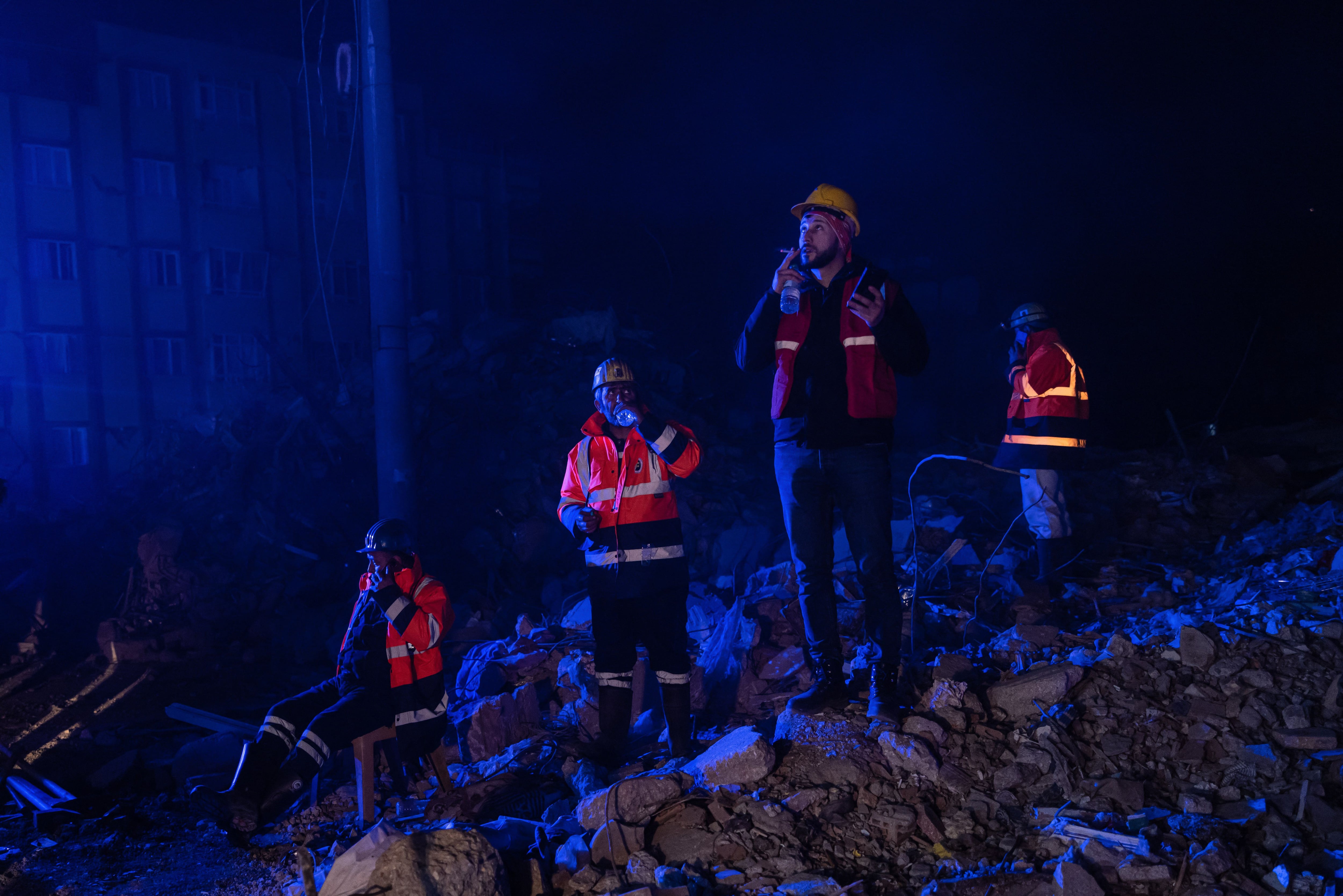 Los equipos de rescate descansan mientras otros buscan víctimas en un edificio derrumbado después de que un segundo terremoto de magnitud 6,4 sacudiera la provincia de Hatay, en el sur de Turquía, en Antakya, el 20 de febrero de 2023.