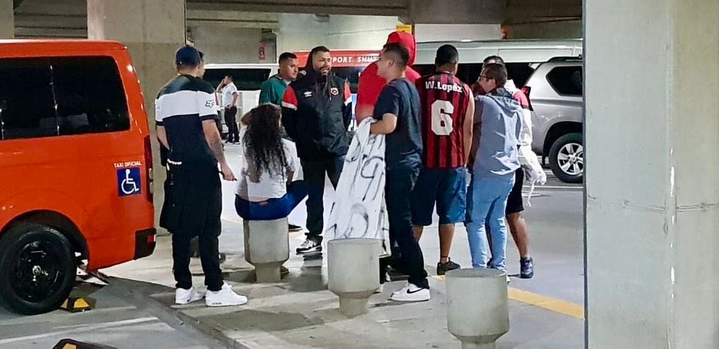 Aficionados de Alajuelense, con pancartas en mano, se encontraron en el parqueo del aeropuerto Juan Santamaría, a la espera del equipo luego de la derrota ante New England.
