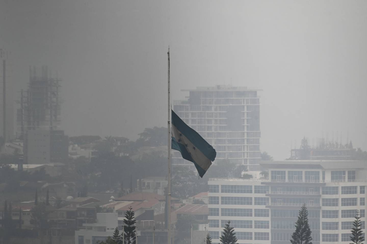 La bandera de Honduras ondea en medio de una densa capa de humo en Tegucigalpa.
