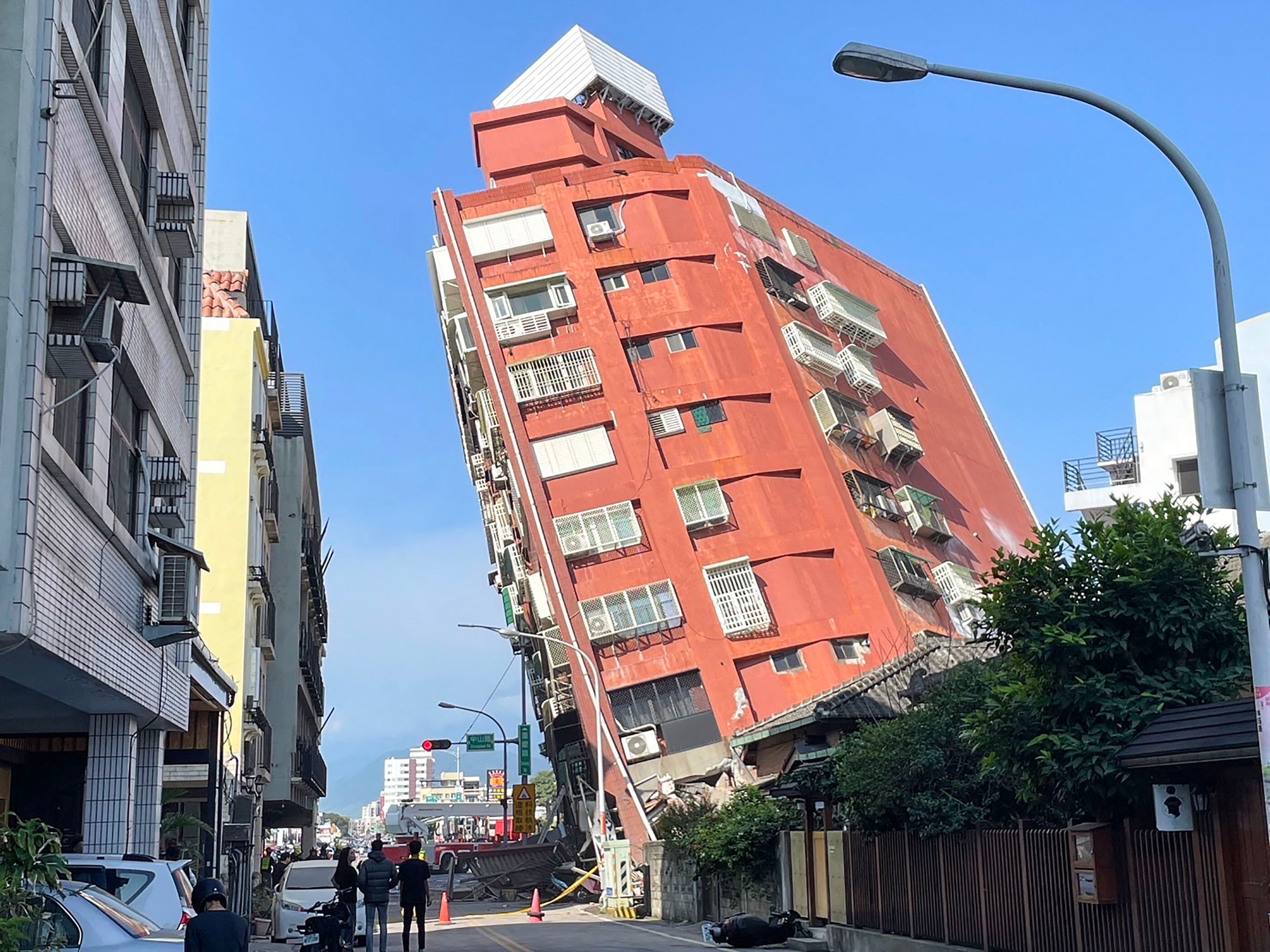 Esta foto tomada por la Agencia Central de Noticias de Taiwán (CNA) el 3 de abril de 2024 muestra a personas mirando un edificio dañado en Hualien, después de que un gran terremoto azotara el este de Taiwán. (Foto de CNA / AFP) 