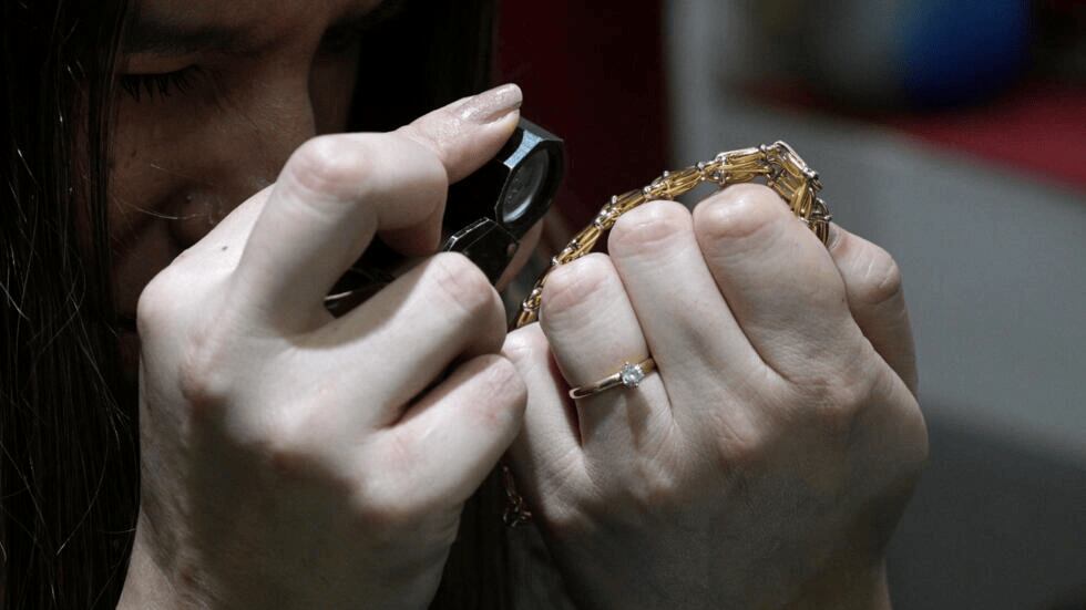 Una tasadora examina una pulsera de oro en un comercio de compra-venta de joyas en Buenos Aires el 6 de junio de 2024 (Foto: Juan Mabromata / AFP)