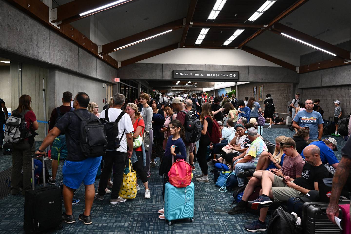 Los pasajeros intentan descansar y dormir después de vuelos cancelados y retrasados ​​mientras otros esperan para abordar vuelos fuera de la isla mientras miles de pasajeros quedaron varados en el aeropuerto de Kahului (OGG) tras los incendios forestales en el oeste de Maui