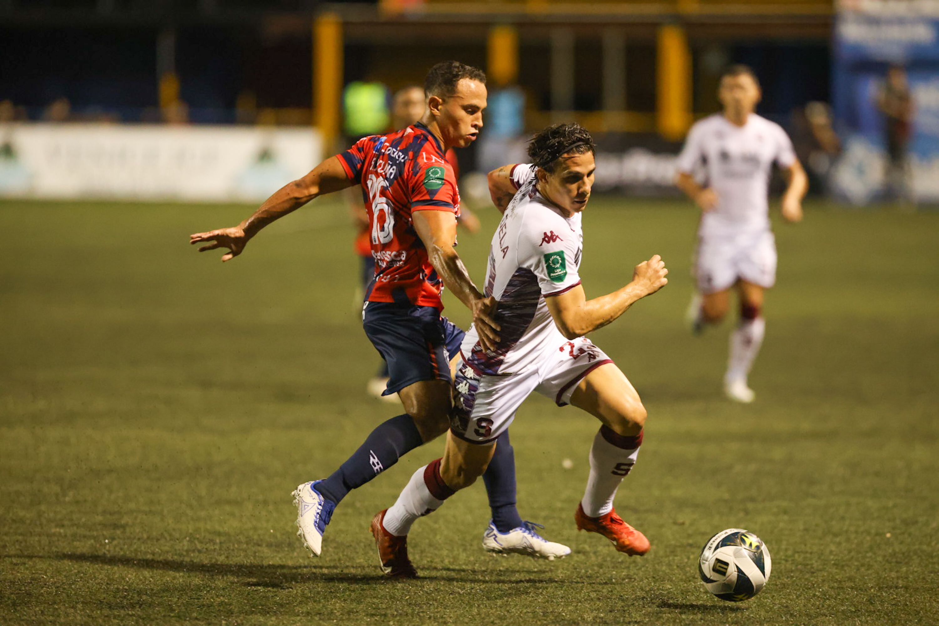 Sebastián Acuña intenta frenar al cubano Luis Paradela. Saprissa derrotó 0-1 a San Carlos en el juego de ida de las semifinales del Torneo Clausura 2024. 