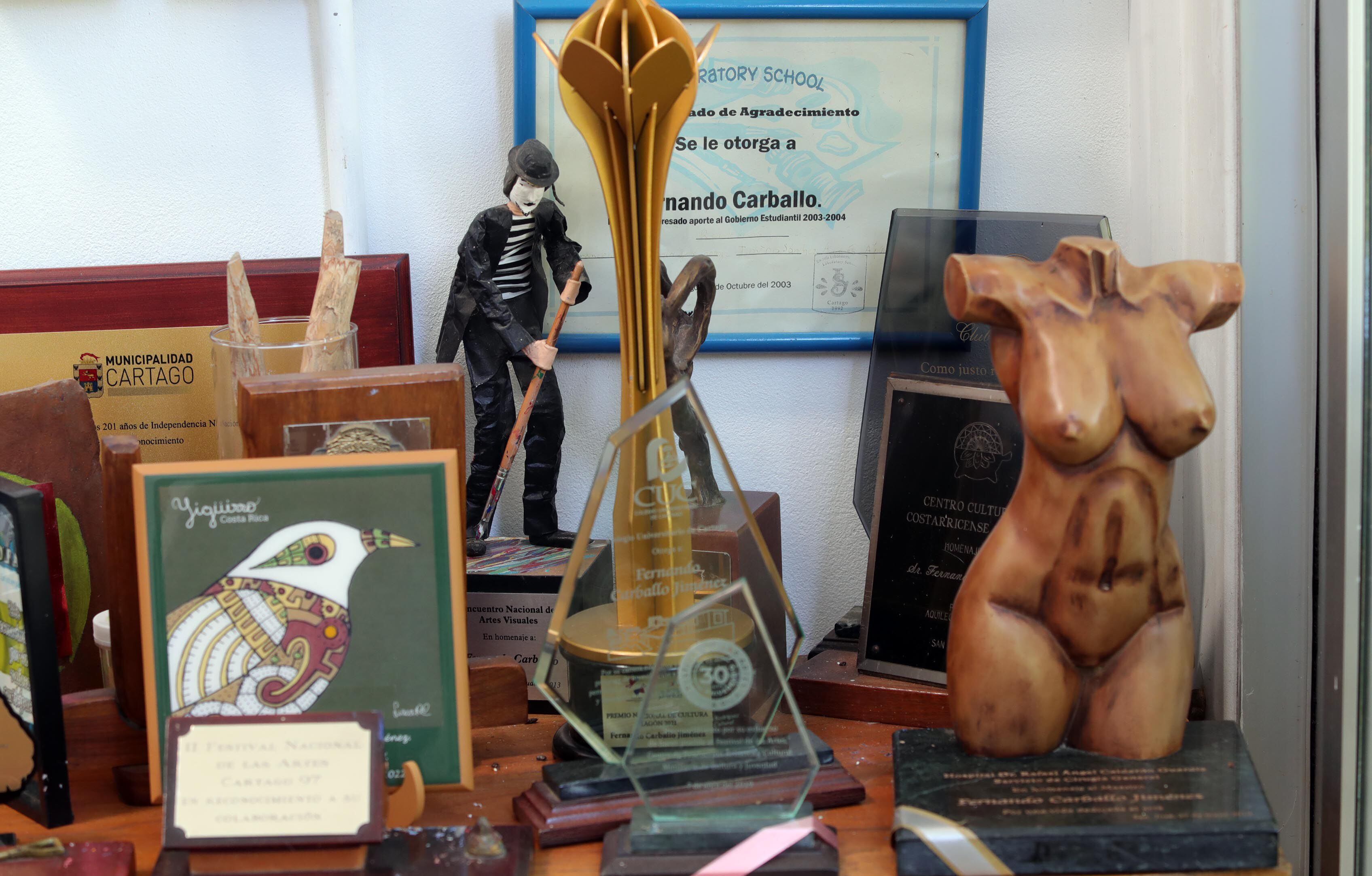 En su taller, se acumulan los reconocimientos a la labor de Carballo. Aquí vemos el Premio Magón (estatuilla de metal) y un homenaje del Colegio Universitario de Cartago, entre otros. 
