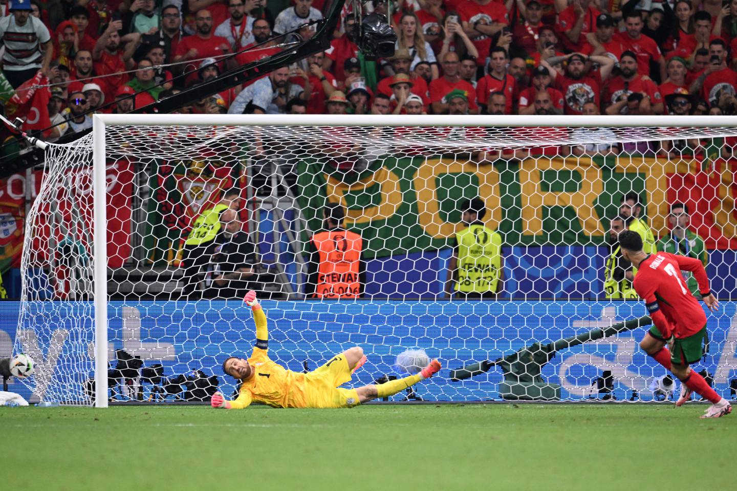 Slovenia's goalkeeper #01 Jan Oblak (L) fails to save a shot from the penalty shout-out kicked by Portugal's forward #07 Cristiano Ronaldo (R) during the UEFA Euro 2024 round of 16 football match between Portugal and Slovenia at the Frankfurt Arena in Frankfurt am Main on July 1, 2024. (Photo by Kirill KUDRYAVTSEV / AFP)