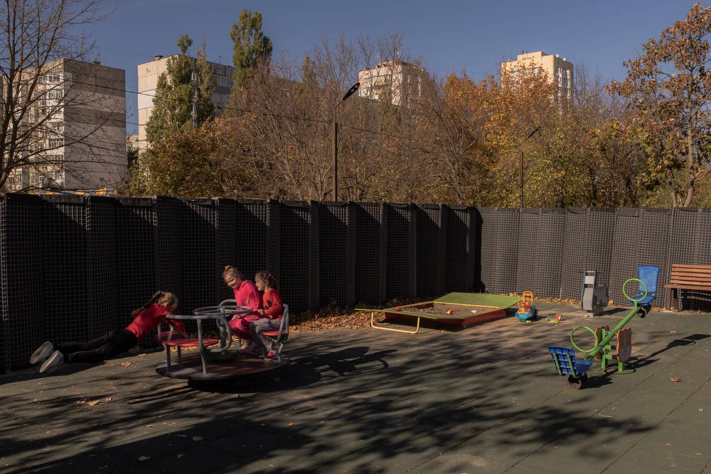 Niñas juegan en un parque infantil rodeado por una valla protectora contra los bombardeos, en la ciudad sureña de Kherson.