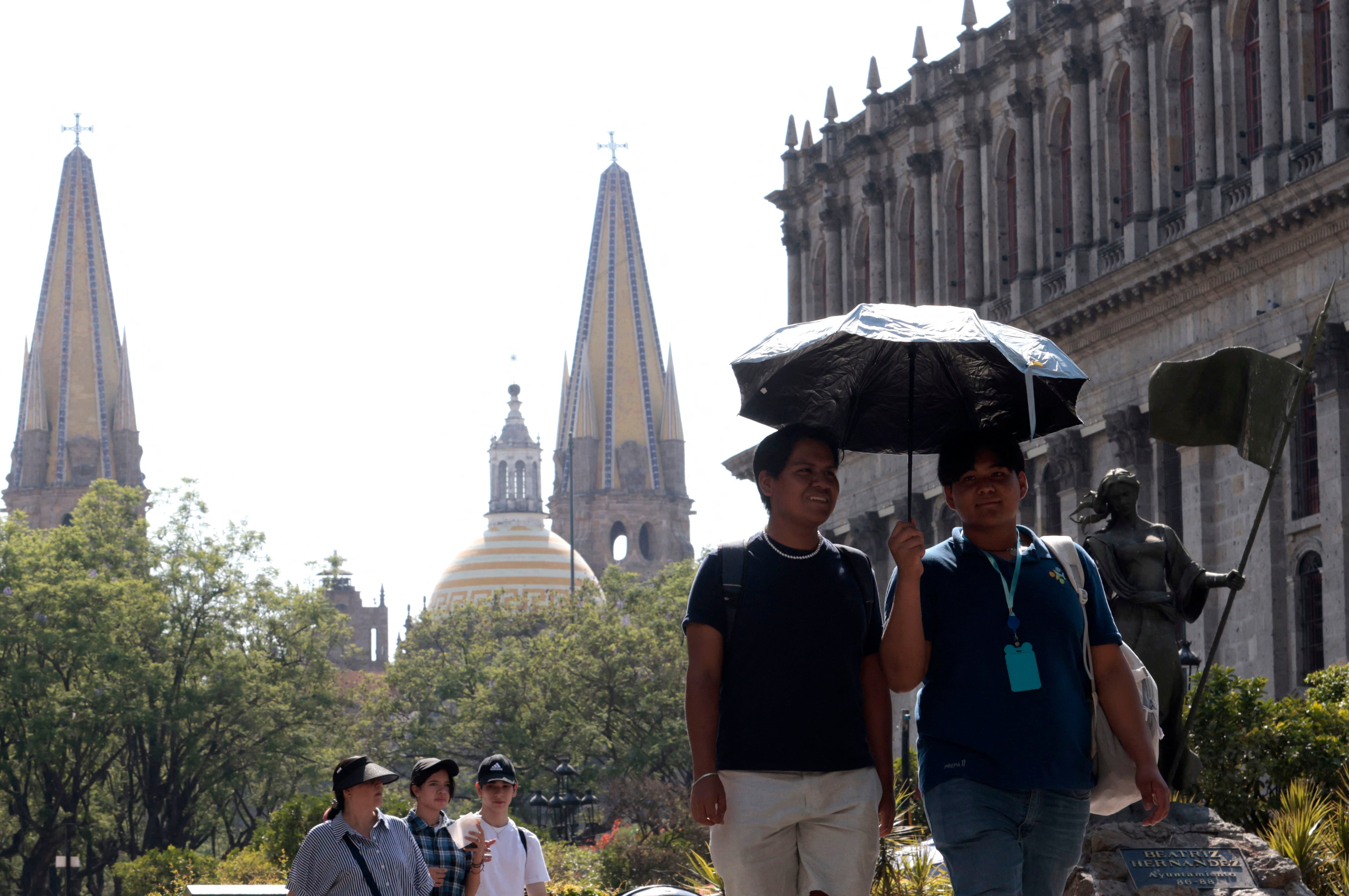 Las personas se protegen del inclemente sol que cobija la Ciudad de México. Las altas temperaturas han resultado mortales. Foto: AFP