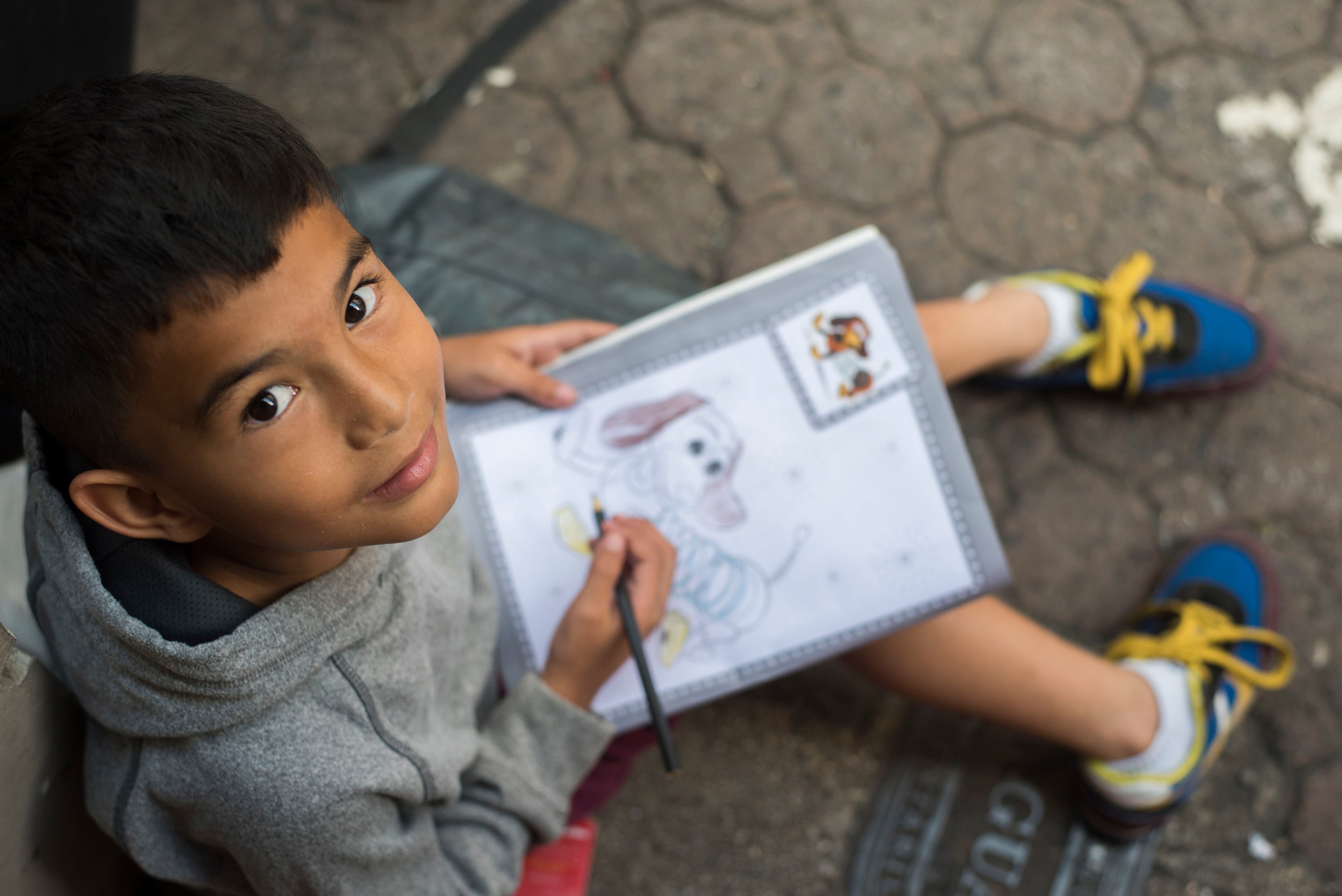 Un cuaderno lleno de ilustraciones de Disney es lo que mantiene entretenido a Abel durante las horas en que su papá reúne dinero en el centro de San José.