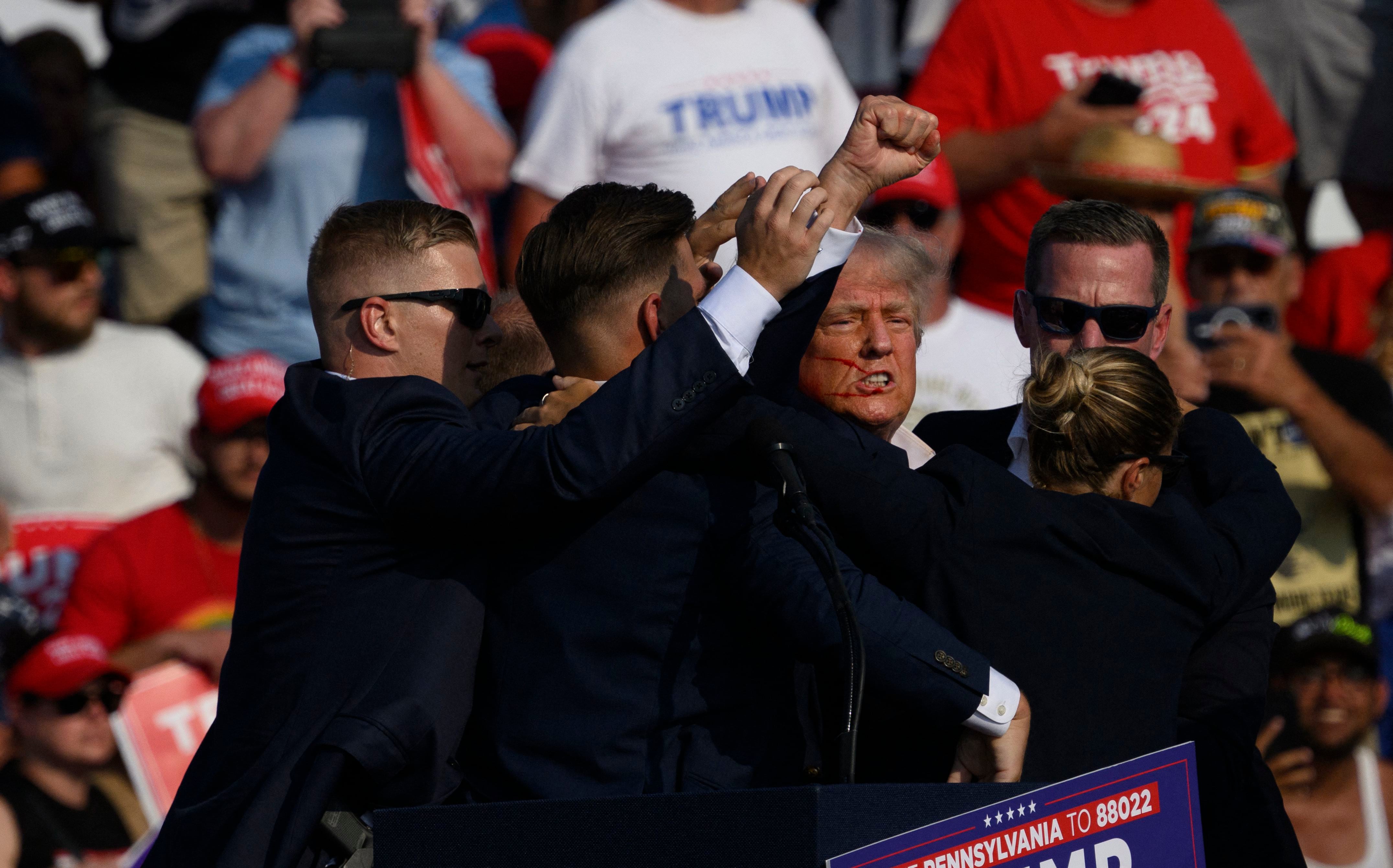 Agentes del Servicio Secreto rodean al ex presidente y candidato presidencial republicano Donald Trump en el escenario después de resultar herido durante un mitin el 13 de julio de 2024 en Butler, Pensilvania.