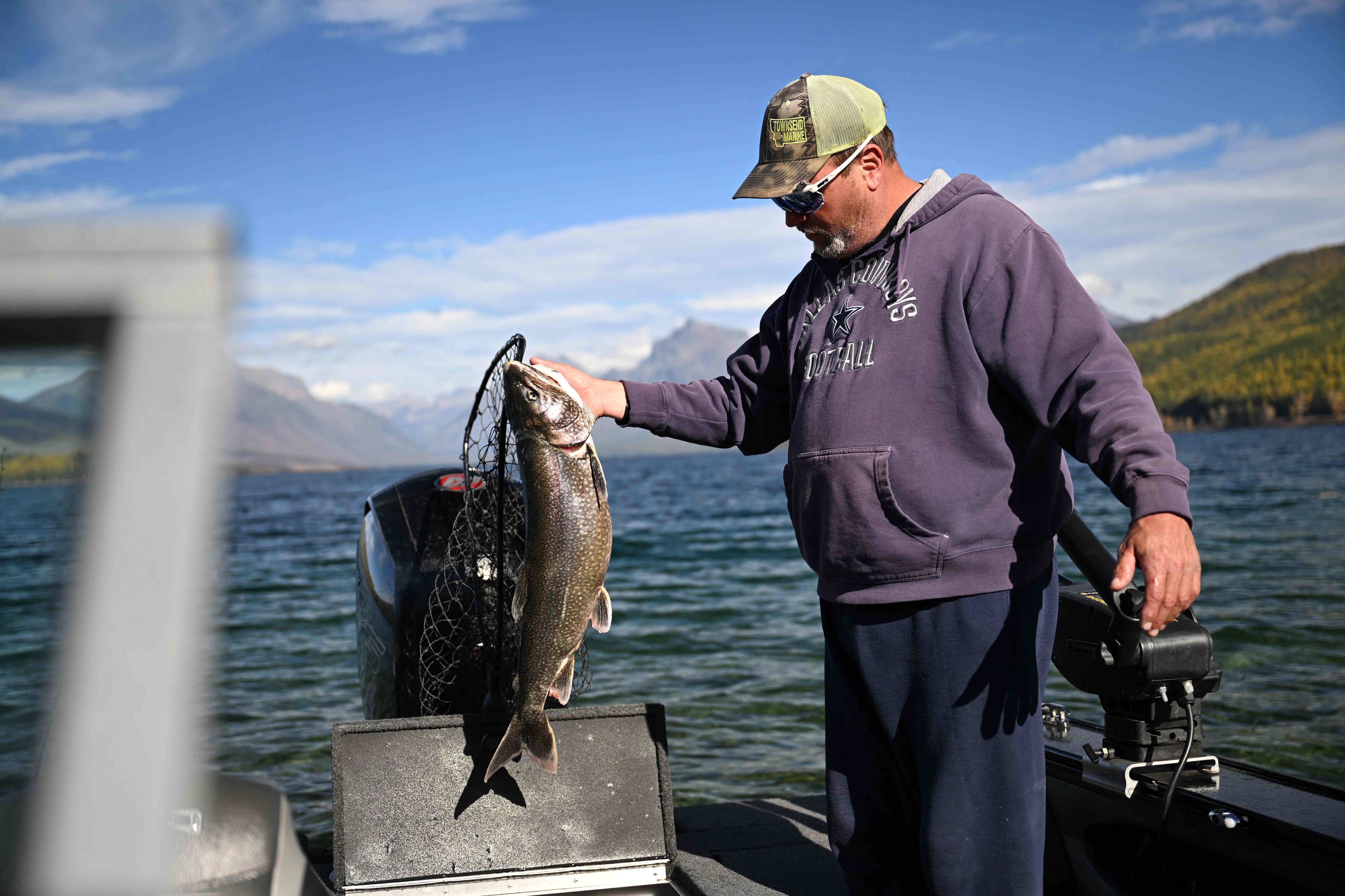Un pescador, que se negó a dar su nombre, muestra una trucha de lago, considerada una especie invasora, que pescó en el lago McDonald en el Parque Nacional Glacier en Montana el 18 de octubre de 2023. (Foto de JOSH EDELSON / AFP)
