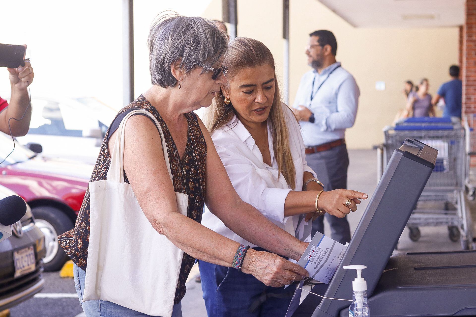 Mayela Jiménez Vega (de lentes), de 74 años, fue la primera que simuló el voto electrónico en Sabanilla, este sábado 2 de enero, guiada por una funcionaria del TSE. Foto: Lilly Arce.