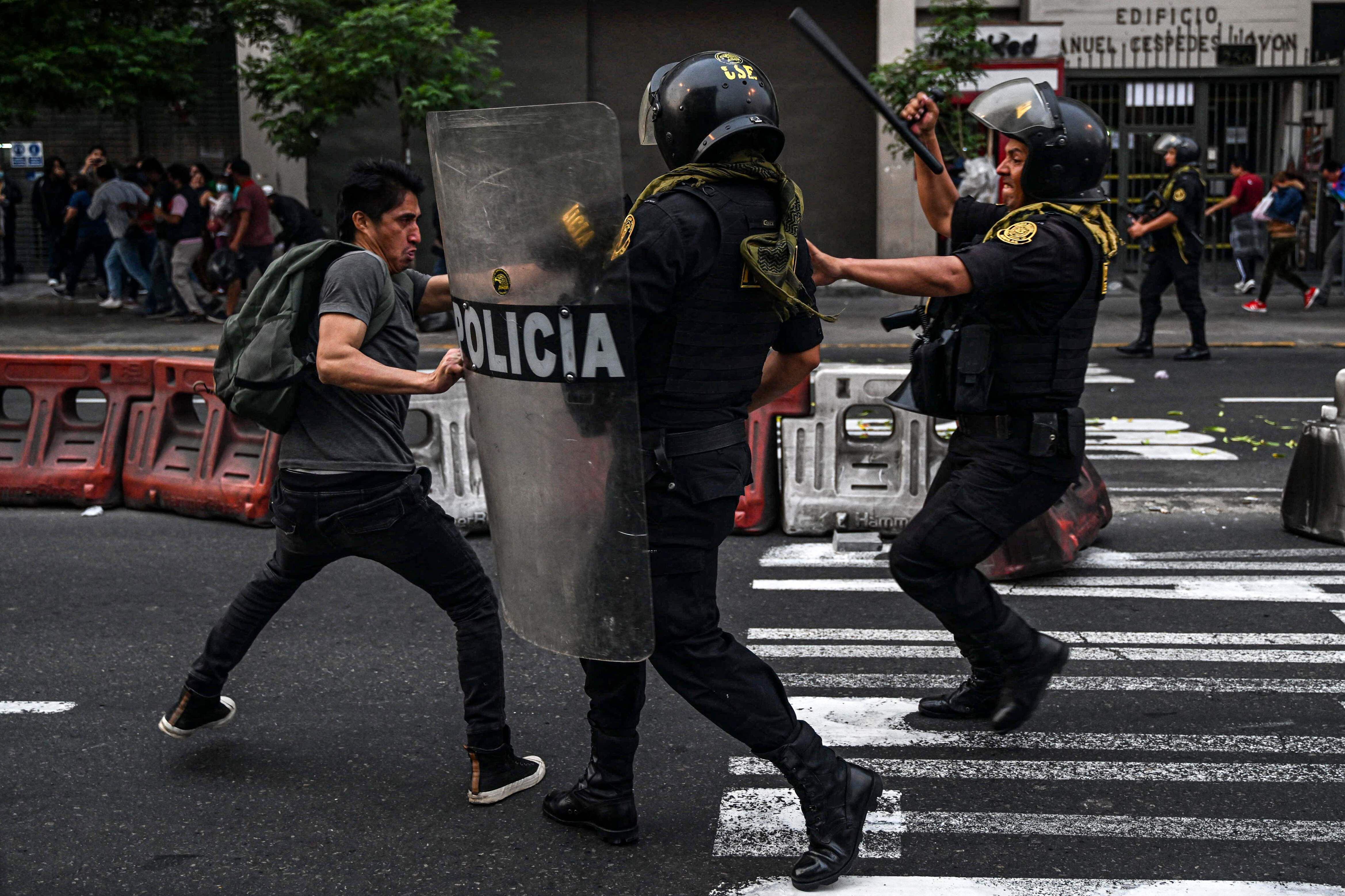 TOPSHOT - A man clashes with riot police during a demonstration demanding the release of ex-President Pedro Castillo and the closure of the Peruvian Congress, in Lima, on December 8, 2022, a day after Castillo's impeachment. - Castillo was replaced by his deputy on the eve, in a dizzying series of events in the country that has long been prone to political upheaval. Peru has had six presidents in six years in a headspinning political environment where governments topple like dominos, many dogged by corruption scandals in a country with a massive gulf between rich and poor. (Photo by Ernesto BENAVIDES / AFP)