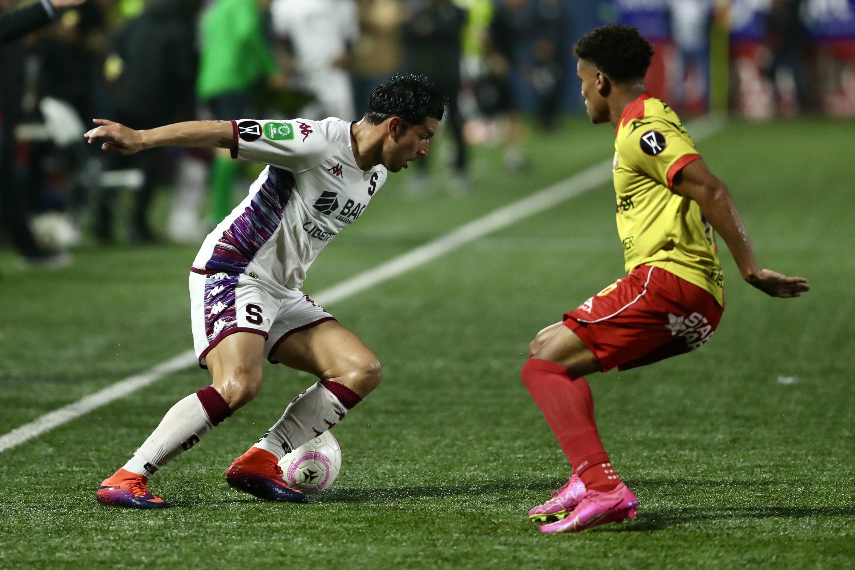 Ariel Rodríguez intenta dejar atrás la marca del defensor del Herediano  Darril Araya. El Team derrotó 2-0 al Saprissa.