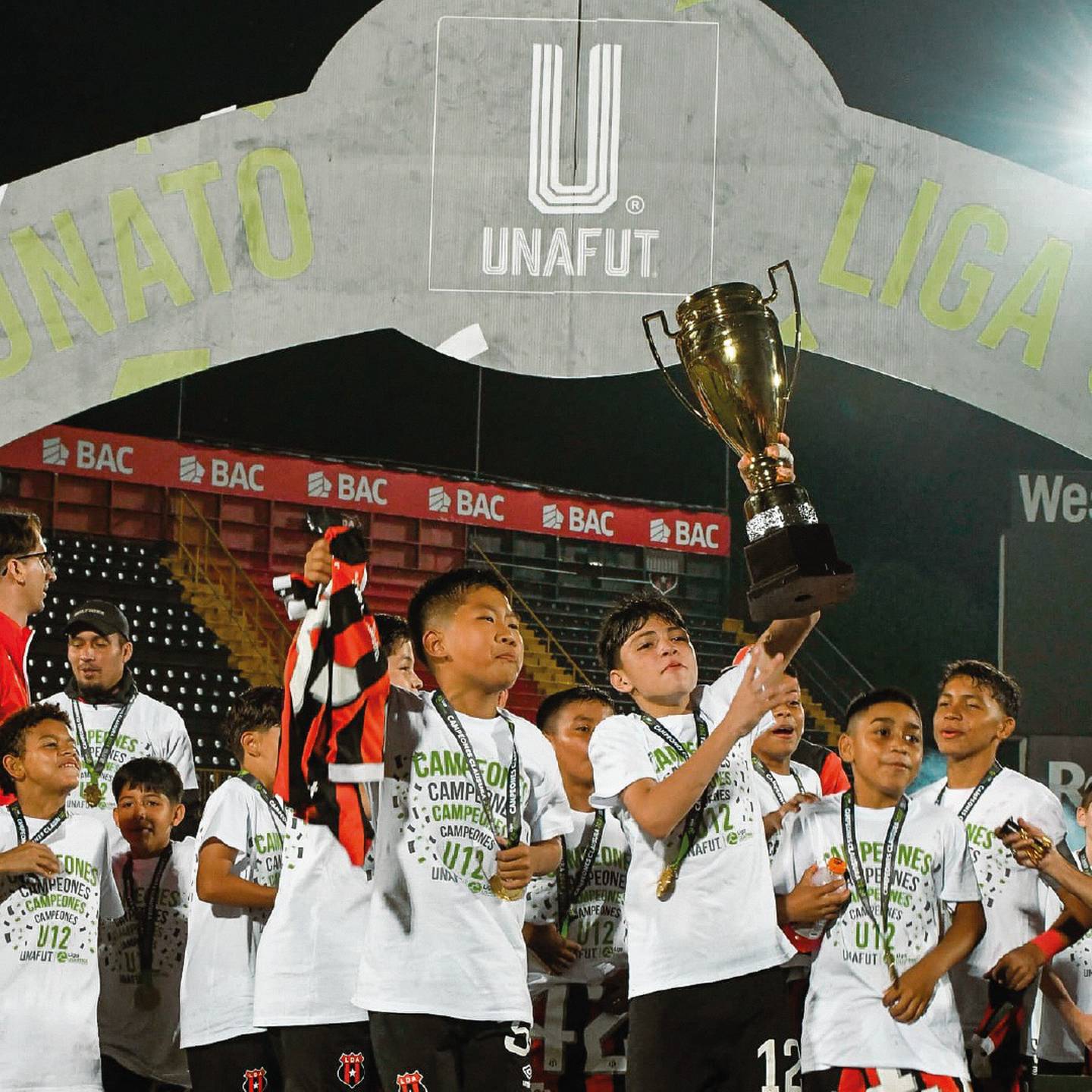 Dylan Liu con camisa en mano y Steven Delgado levanta la copa que ganó Liga Deportiva Alajuelense en U-12.