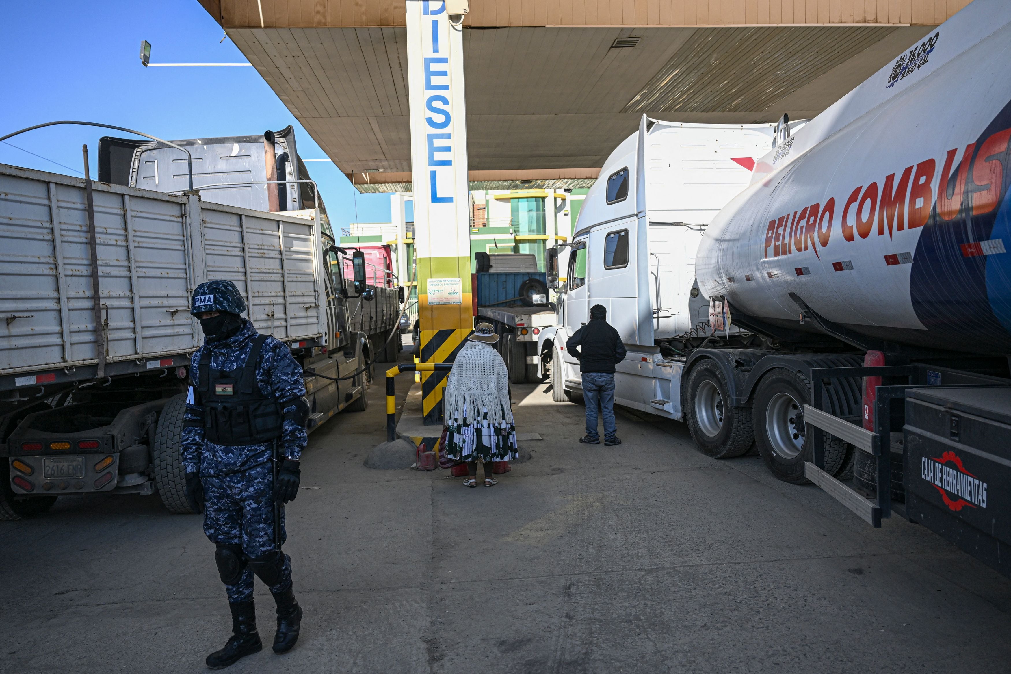 Un oficial militar vigila mientras los conductores llenan sus camiones con diésel en una gasolinera en El Alto, Bolivia, el 29 de junio de 2024. (Foto de ERNESTO BENAVIDES / AFP)